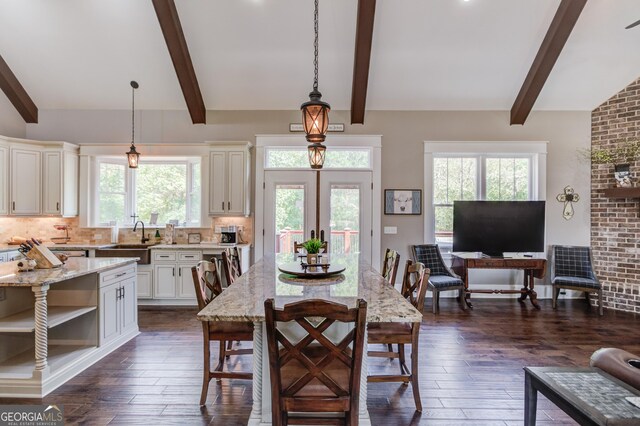 dining room with beam ceiling, brick wall, sink, and dark hardwood / wood-style flooring