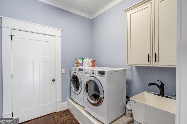 clothes washing area with wood-type flooring, sink, washer and clothes dryer, crown molding, and cabinets