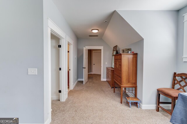 hallway featuring light carpet and lofted ceiling