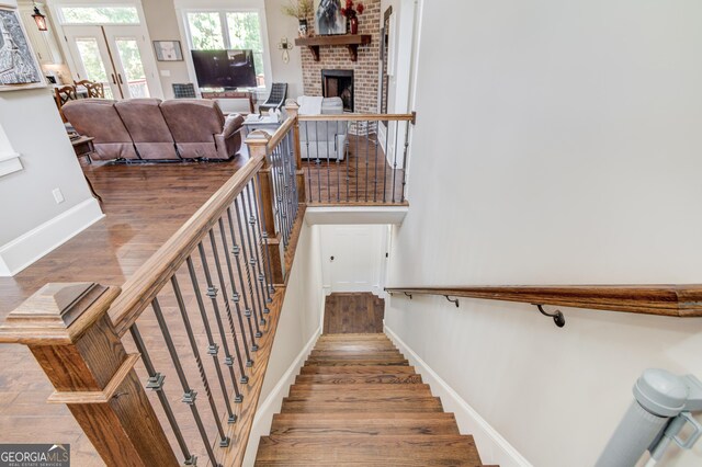 stairway featuring french doors, wood-type flooring, and a brick fireplace