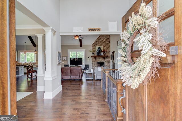 foyer with ornate columns, crown molding, a high ceiling, and dark hardwood / wood-style flooring