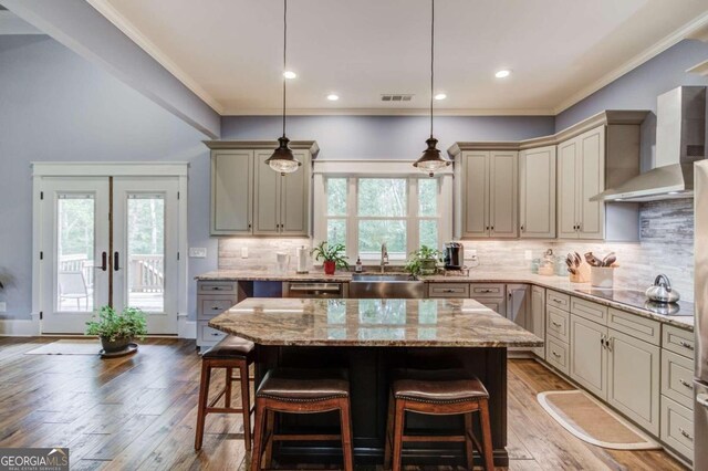 kitchen featuring wall chimney exhaust hood, hardwood / wood-style floors, a center island, and a breakfast bar