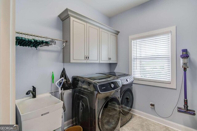 washroom with sink, independent washer and dryer, and cabinets