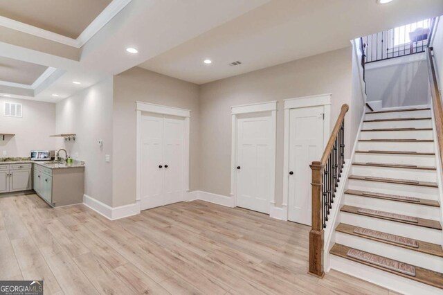 interior space featuring sink, light wood-type flooring, and a raised ceiling