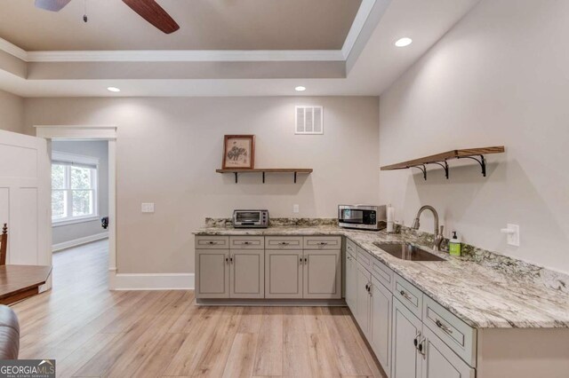 kitchen featuring sink, light stone counters, light hardwood / wood-style floors, and ceiling fan