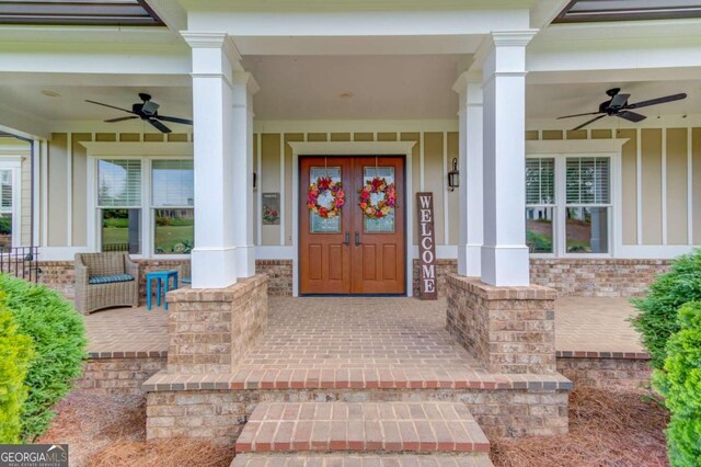 entryway featuring dark hardwood / wood-style floors, decorative columns, crown molding, a brick fireplace, and ceiling fan with notable chandelier