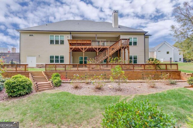 rear view of house featuring a wooden deck and a lawn