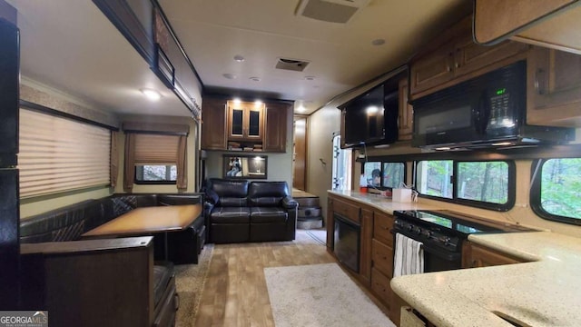 kitchen featuring light stone countertops, dark brown cabinets, light wood-type flooring, and range