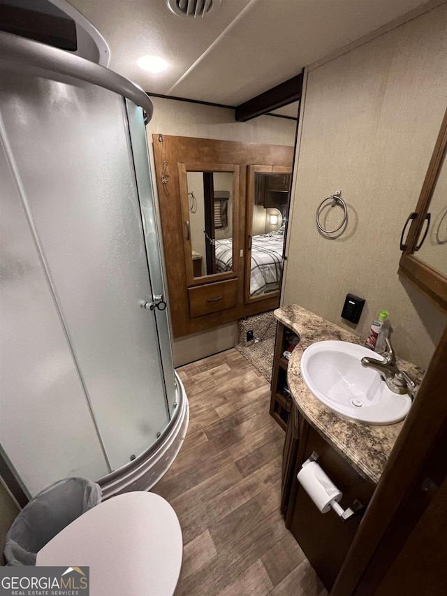 bathroom with vanity, toilet, an enclosed shower, and hardwood / wood-style floors