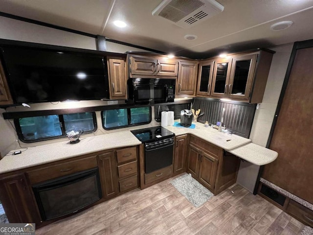 kitchen with light hardwood / wood-style floors, tasteful backsplash, black appliances, and dark brown cabinets