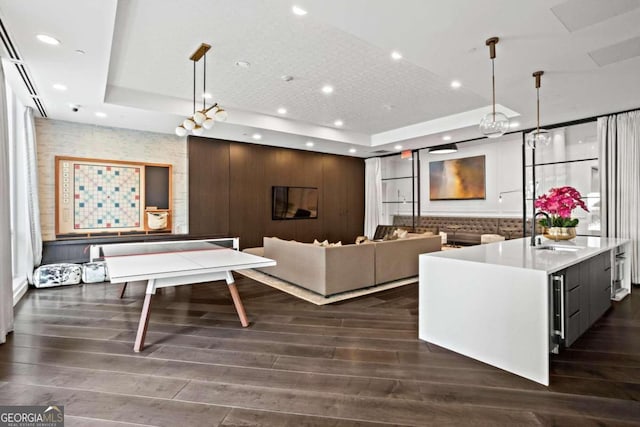 living room featuring dark hardwood / wood-style floors, sink, and a tray ceiling