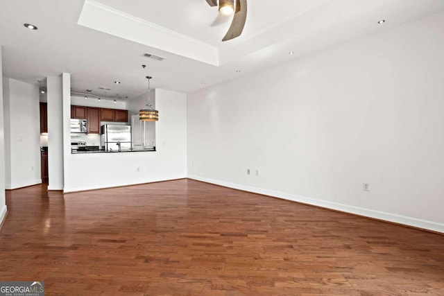 unfurnished living room with ceiling fan with notable chandelier, a raised ceiling, and dark hardwood / wood-style floors