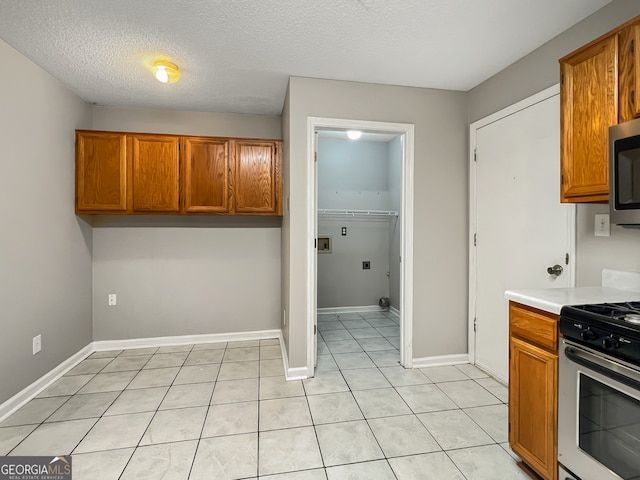 kitchen with a textured ceiling, range with gas stovetop, and light tile patterned floors