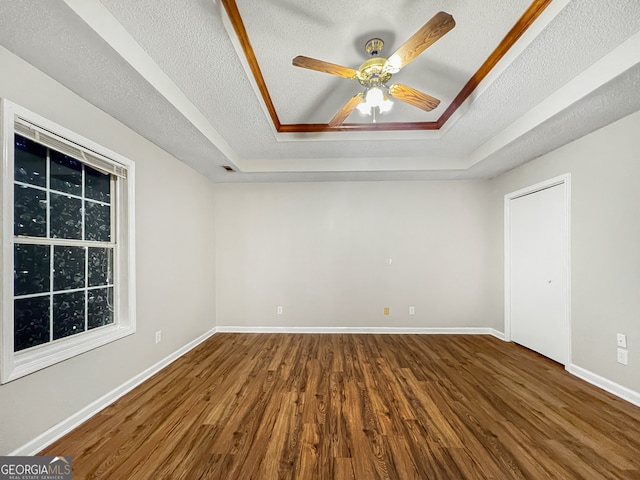 spare room featuring a textured ceiling, a tray ceiling, wood-type flooring, and ceiling fan