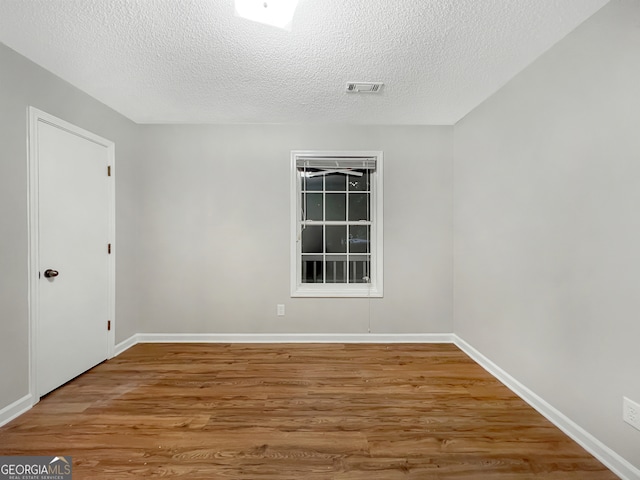 unfurnished room featuring wood-type flooring and a textured ceiling