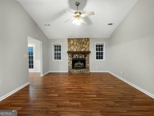 unfurnished living room featuring dark wood-type flooring, ceiling fan, a stone fireplace, and high vaulted ceiling