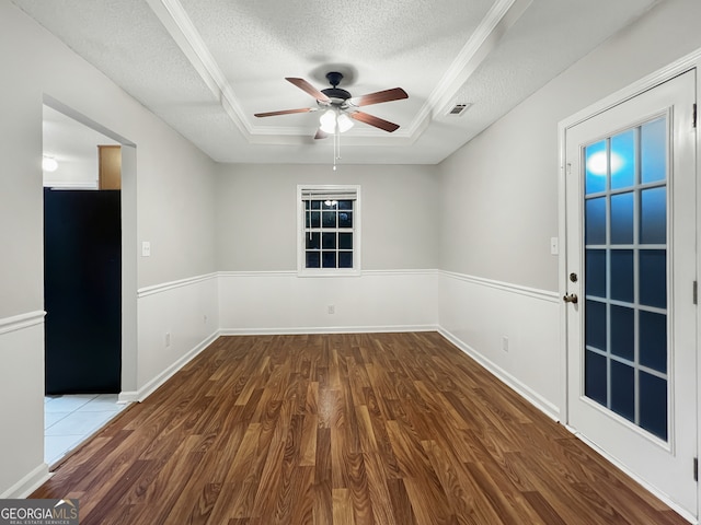 spare room with a textured ceiling, a raised ceiling, wood-type flooring, and ceiling fan