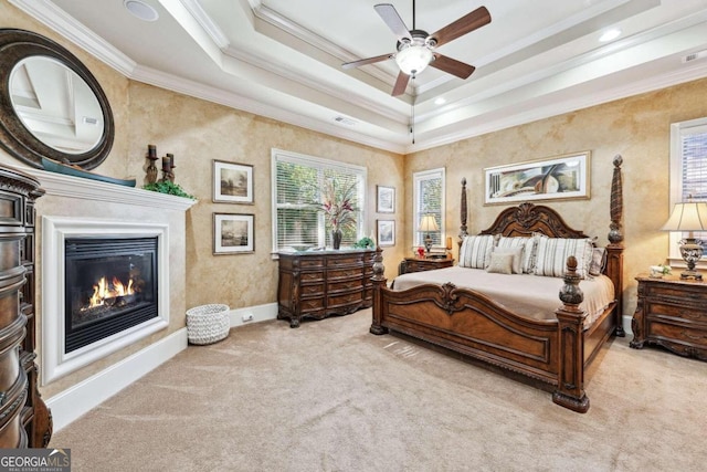 bedroom featuring crown molding, light carpet, a tray ceiling, and ceiling fan