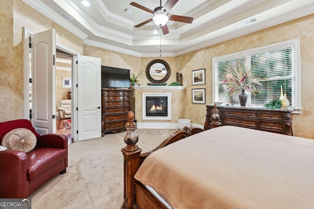 bedroom featuring crown molding, light carpet, a tray ceiling, and ceiling fan