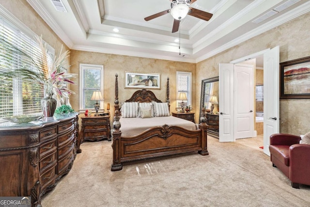 carpeted bedroom with connected bathroom, ornamental molding, a tray ceiling, and ceiling fan