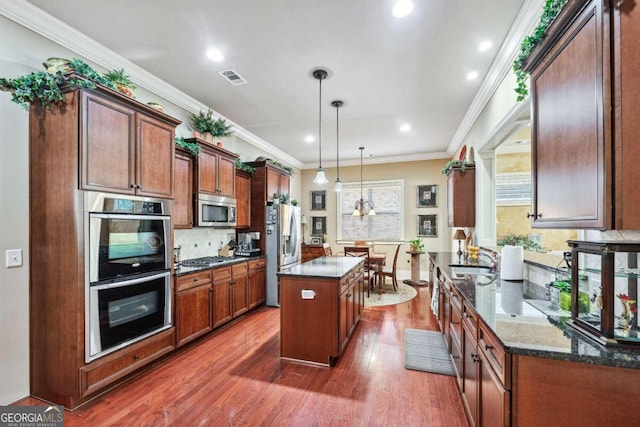 kitchen featuring a center island, hanging light fixtures, stainless steel appliances, dark wood-type flooring, and crown molding