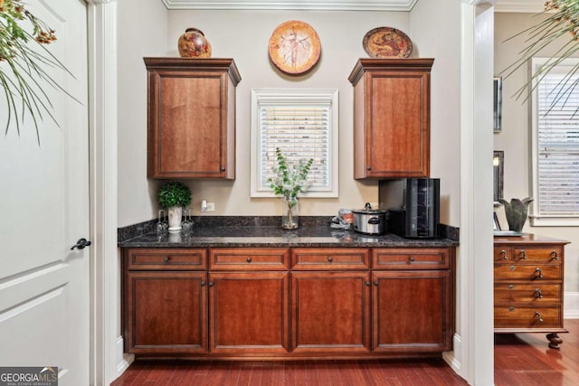 kitchen with dark wood-type flooring, dark stone countertops, and ornamental molding