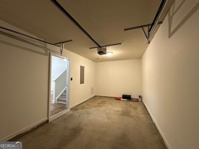 garage featuring electric panel, baseboards, and a garage door opener