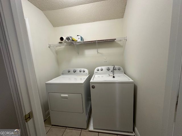 clothes washing area featuring light tile patterned floors, laundry area, a textured ceiling, and independent washer and dryer