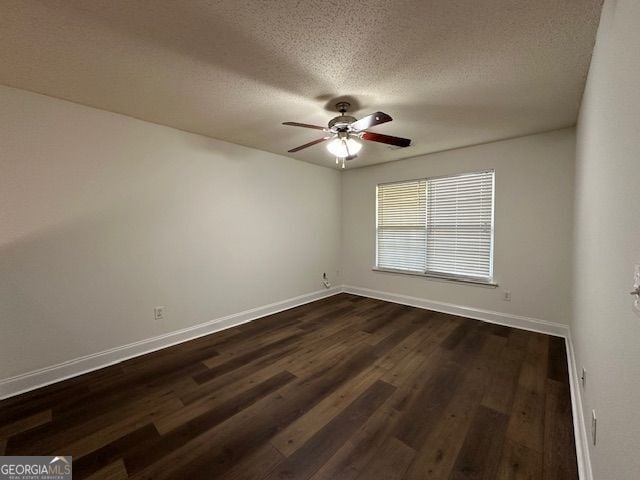 spare room with a textured ceiling, dark wood finished floors, a ceiling fan, and baseboards