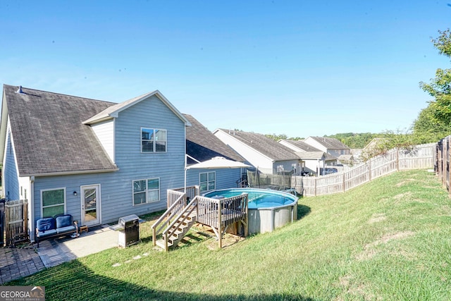 rear view of house with a patio, a lawn, and a fenced in pool