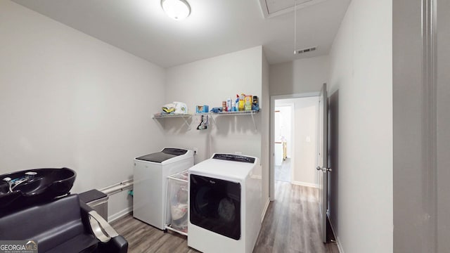 laundry room with washing machine and clothes dryer and hardwood / wood-style flooring