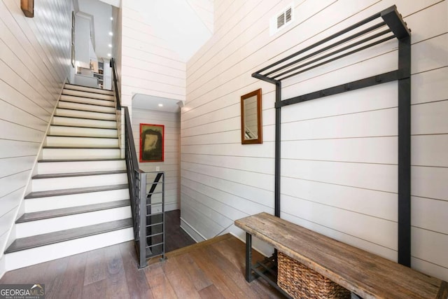 mudroom with wooden walls, dark hardwood / wood-style floors, and a high ceiling