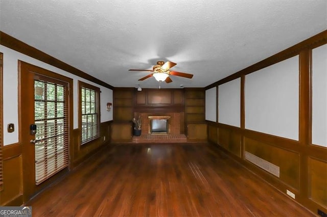 unfurnished living room with a textured ceiling, a brick fireplace, and dark hardwood / wood-style floors