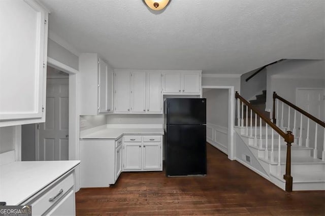 kitchen featuring a textured ceiling, white cabinets, dark hardwood / wood-style floors, and black fridge