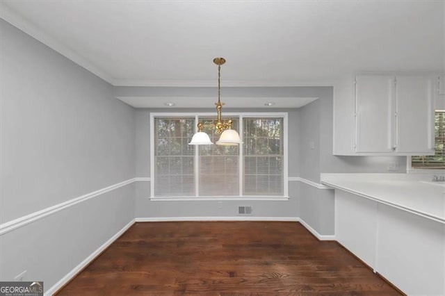 unfurnished dining area with a notable chandelier, dark hardwood / wood-style floors, a healthy amount of sunlight, and crown molding