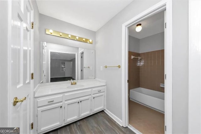 bathroom featuring vanity, a tile shower, and wood-type flooring