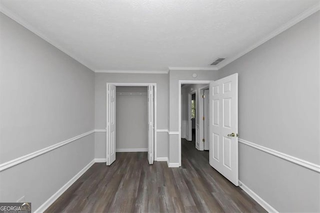 unfurnished bedroom featuring ornamental molding, dark wood-type flooring, and a closet