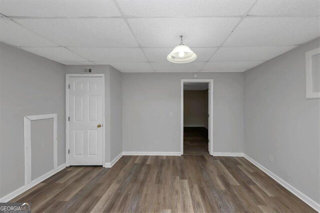 unfurnished room featuring dark wood-type flooring and a paneled ceiling