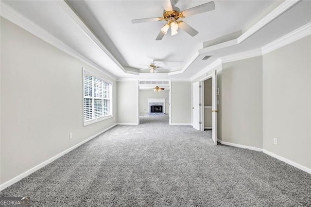 unfurnished living room featuring carpet flooring, a raised ceiling, and ornamental molding