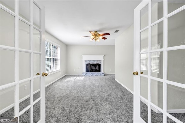 unfurnished living room featuring a high end fireplace, carpet flooring, and ceiling fan