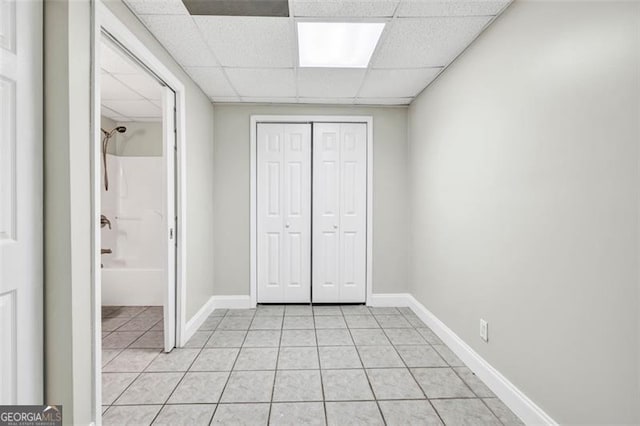 unfurnished bedroom featuring a closet, a paneled ceiling, and light tile patterned flooring