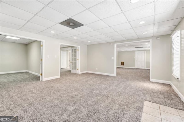 basement featuring light carpet and a paneled ceiling