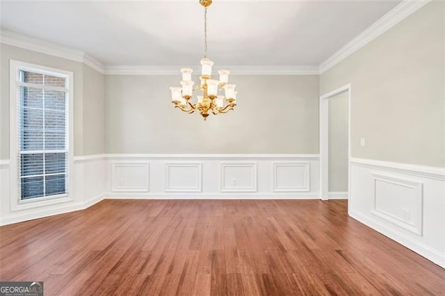 unfurnished room featuring an inviting chandelier, crown molding, and hardwood / wood-style floors