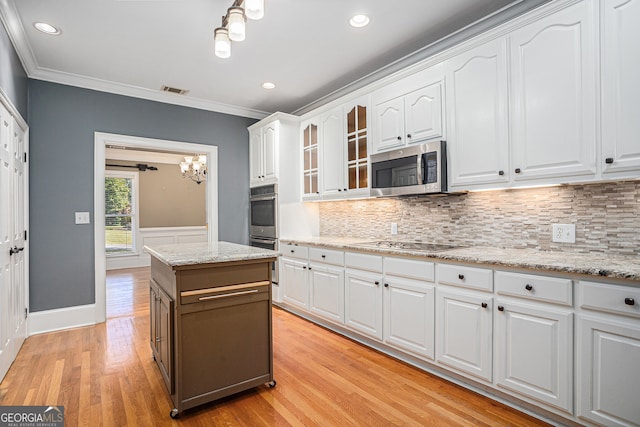 kitchen with appliances with stainless steel finishes, light wood-type flooring, a kitchen island, white cabinetry, and crown molding