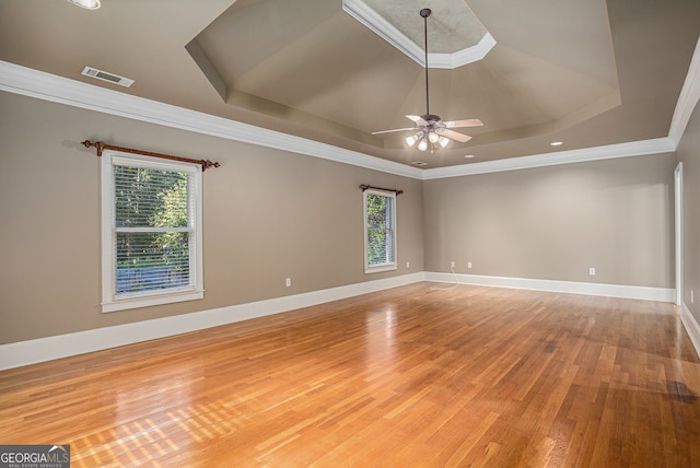 unfurnished room featuring hardwood / wood-style floors, crown molding, a tray ceiling, and ceiling fan