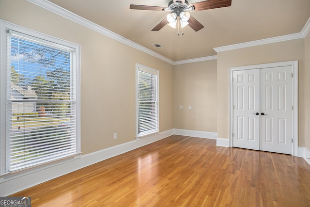 unfurnished bedroom featuring ceiling fan, crown molding, wood-type flooring, and multiple windows