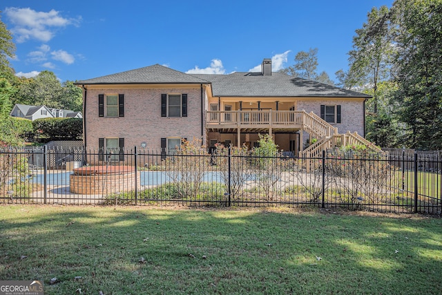 back of property with a fenced in pool and a lawn