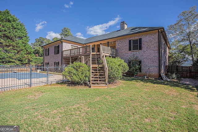 rear view of house with a pool side deck and a yard