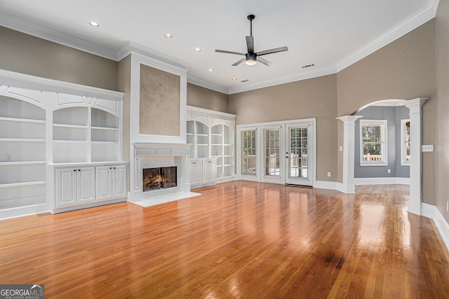 unfurnished living room featuring a high ceiling, ornate columns, light hardwood / wood-style flooring, ornamental molding, and ceiling fan