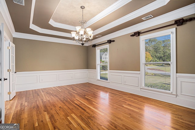 unfurnished room with ornamental molding, a chandelier, wood-type flooring, and a raised ceiling